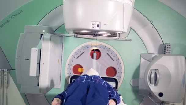 Il paziente maschio viene irradiato da una macchina acceleratrice lineare funzionante. Concetto di medicina moderna . — Video Stock