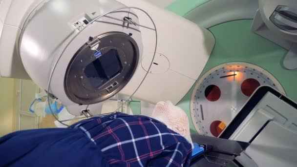 Linac arbetande delar roterar runt en liggande manlig patient — Stockvideo