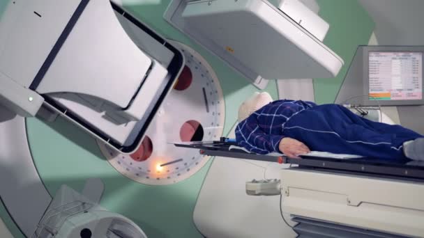 Ασθενής που είναι ξαπλωμένος σε ένα τραπέζι είναι να ακτινοβοληθεί κατά τη διάρκεια της διαδικασίας επεξεργασίας — Αρχείο Βίντεο