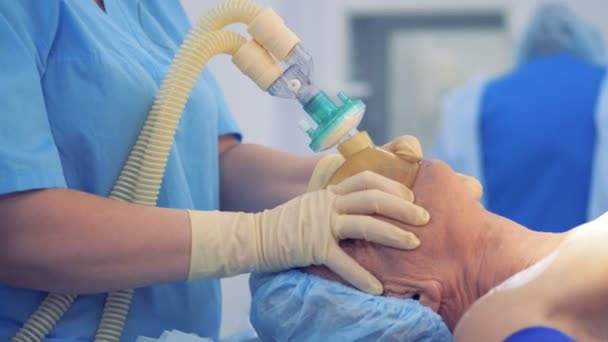 Bir doktor hasta yüz oksijen maskesi onu anestezi vermek için baskı yapıyor — Stok video