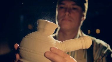 O karanlık atölyesinde çalışırken yakın bir ciddi potters yüz görünümü ayrıntılı. 4k.