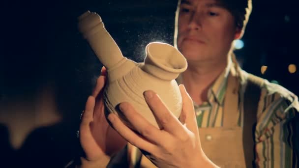 Portret van de ambachtsman. Een nauwe gedetailleerde weergave op een ernstige pottenbakkers gezicht als hij in de donkere workshop werkt. — Stockvideo