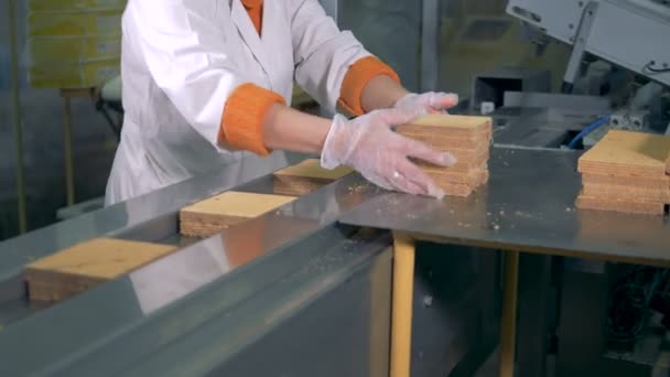 A factory worker is putting blocks of waffles onto the conveyor belt — Stock Video