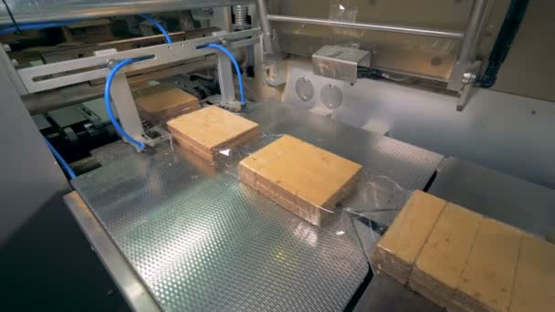 Whole line of plastic wrap with waffles in it is getting cut and sealed into separate blocks — Stock Video