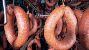 Tütsülenmiş sosis halkaları üzerinde metal duruyor, standları hareketli kamera asılı olan.