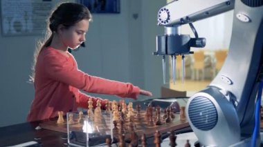 Küçük zeki kız ve robotik kol okulda satranç.