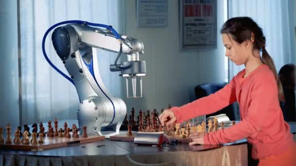 Concept de génie de l'enfant. Jeune fille intelligente jouant aux échecs avec un robot d'échecs moderne. 4K . — Video