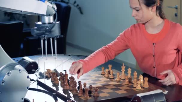 Niña preparando un tablero de ajedrez para jugar al ajedrez con un robot . — Vídeo de stock