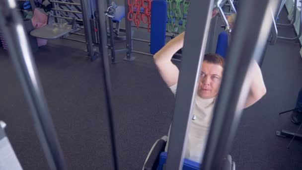 En inaktiverad man lyfta vikter i en gym håller en metall handtag av sina båda händer — Stockvideo