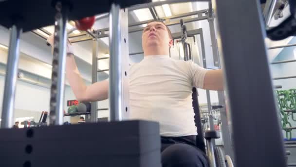 Čelní pohled člověka na vozíku, zvedání břemen s cvičební stroj — Stock video