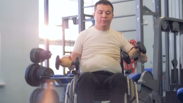 Een volwassen gehandicapte man houdt het opheffen van stom-bells na een korte pauze — Stockvideo