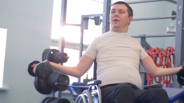 Training session of a disabled man with two dumb-bells in a gym — Wideo stockowe