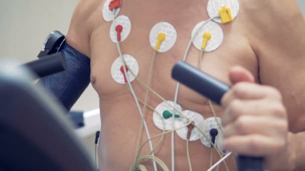 En gammal manlig patient med hjärta sensor på bröstet gör särskilda övningar. — Stockvideo