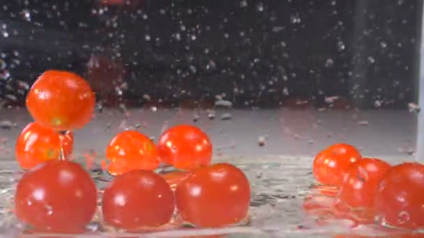 Processus de chute d'une pile de tomates dans un récipient vitreux avec un peu d'eau — Video