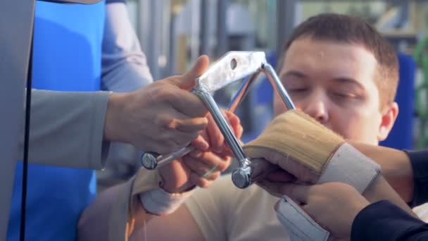 Trainers help disabled man in fixing hands clamps. — Stock Video