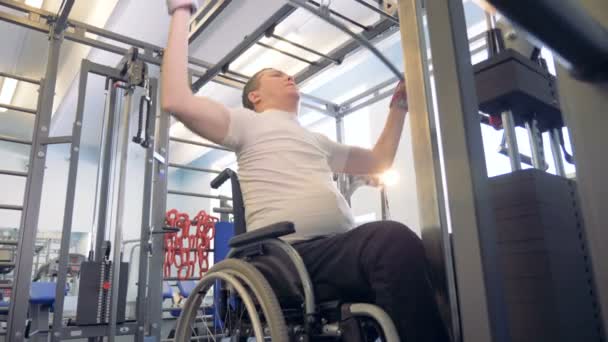 Gehandicapte man maakt oefeningen in een sportschool op training apparaten. — Stockvideo