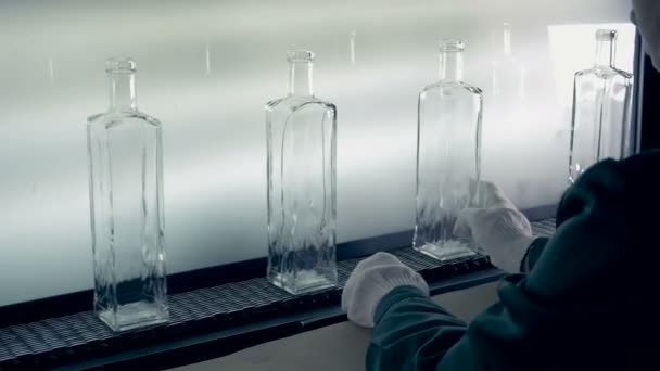 Сотрудник завода контролирует качество вновь изготовленных бутылок и перемещает их — стоковое видео