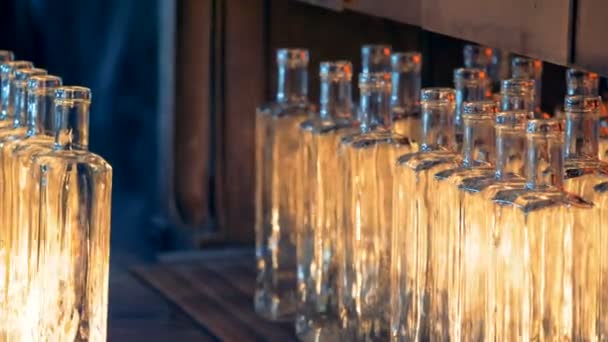 Botellas de vidrio reflejan la luz del fuego y están siendo movidos por la prensa — Vídeo de stock