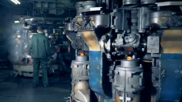 Several industrial machines for making and hardening glass bottles are functioning and a male worker is controlling the process — Stock Video