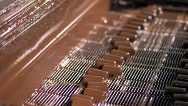 Flüssige Schokolade ergießt sich in der Fabrik über Bonbons. Nahaufnahme. — Stockvideo