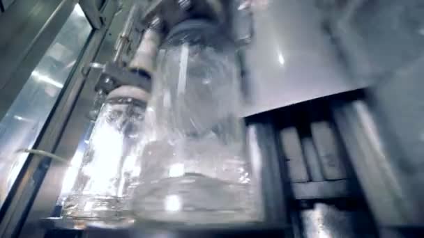 Las botellas se mueven mientras una máquina las llena de alcohol. 4K . — Vídeo de stock