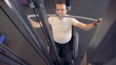 Atlet tekerlekli sandalyede bir spor salonunda sırt kasları güçlendirir.