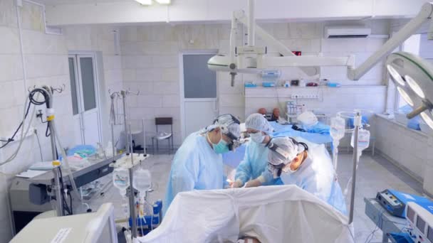 Un equipo de cirujanos está llevando a cabo una operación en un paciente detrás de la cortina en una unidad del hospital — Vídeo de stock