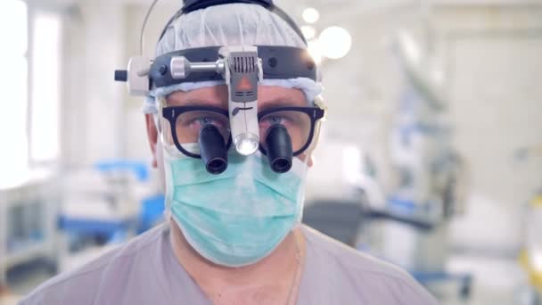 Close-up de um rosto de um médico usando óculos, uma ferramenta especial e uma máscara. Retrato médico profissional . — Vídeo de Stock