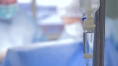 Cerrahlar arka planda çalışan bir grup ile bir tam damla şişesi yakın çekim