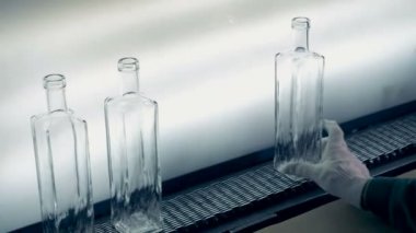 Bir fabrika işçisi cam şişeler hafif bir arka plan üzerinde kusur bulmaya benziyor. 4k.
