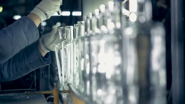 Um trabalhador de fábrica examina o pescoço de garrafas em um transportador em uma fábrica. 4K . — Vídeo de Stock