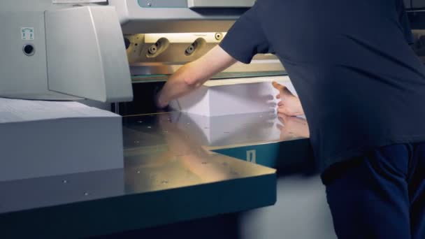 Un employé ajuste deux grandes piles de papier sous une fraise qui les laboure en quatre parties — Video
