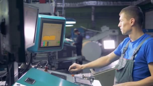 Hombre trabajando con computadora en una tipografía de fábrica de impresión . — Vídeo de stock
