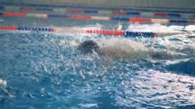 Bir atlet bir havuzu lane üzerinde yüzüyor, yakın çekim.