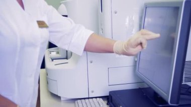 Bir hemşire türleri bir makinede bir kan testi gerçekleştirirken bir monitörde. 4k.