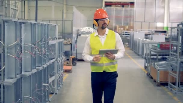 Ein Arbeiter mit Tablet läuft in einem Betrieb, in der industriellen Fertigung, im Lager. — Stockvideo