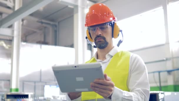 Ένα άνθρωπος που λειτουργεί για το tablet σε μια βιομηχανική εγκατάσταση, κοντινό πλάνο. — Αρχείο Βίντεο