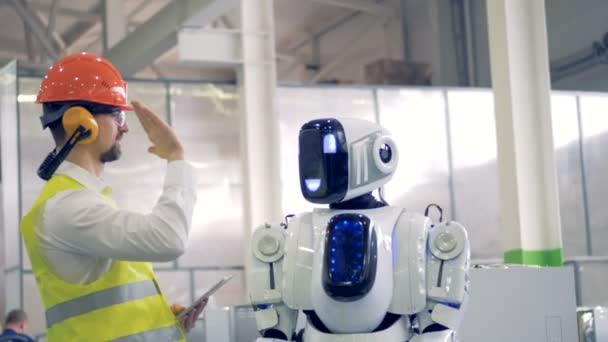 Lidské tovární dělník a android dávají navzájem hi pět v tovární zařízení.