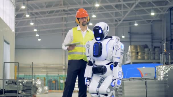 Le travailleur masculin allume un droïde, puis l'accueille dans une usine. 4K . — Video