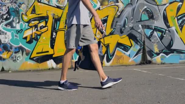 Joven caminando por el suelo de la calle con un bote de aerosol en sus manos — Vídeo de stock