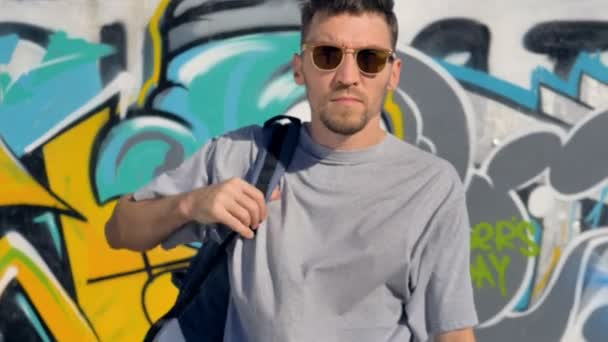 Artista de graffiti se aleja de una pared de graffiti con una mochila en los hombros — Vídeo de stock