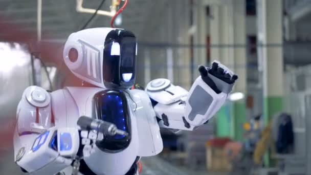 Un robot se repară singur, se închide. Un robot alb folosește un instrument pentru a se repara într-o fabrică . — Videoclip de stoc