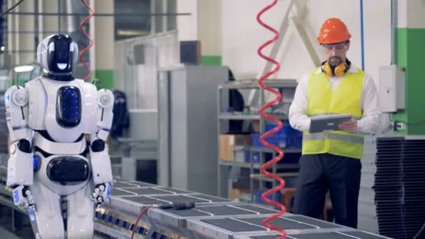 Ingenjör styr roboten arbetar på ett transportband i en fabrik. 4k. — Stockvideo