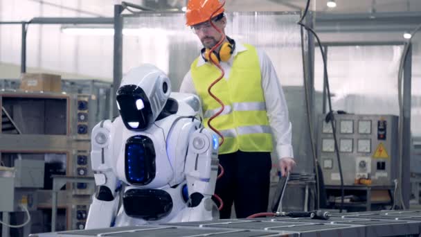 Un trabajador de la fábrica enciende un droide, controlándolo . — Vídeo de stock