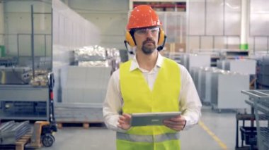 Fabrika işçisi fabrika ve not almak onun tablet bilgisayar aracılığıyla yürüyor