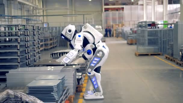 Un robot similar a un humano está poniendo una pieza de montaje y alejándose en un almacén de fábrica . — Vídeo de stock
