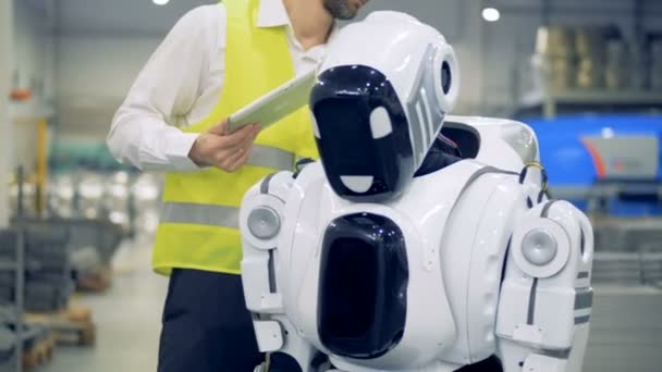 Un employé d'usine masculin allume un cyborg et règle ses paramètres — Video