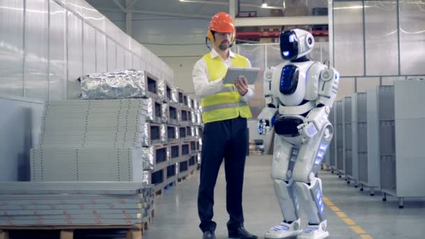 Impiegato di fabbrica e un umanoide stanno comunicando in una struttura di fabbrica . — Video Stock