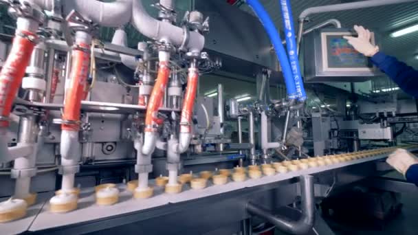 Βιομηχανική μηχανή γεμίζει Κύπελλα γκοφρέτα με λευκό παγωτού ενώ εργάτρια ρύθμιση παραμέτρων — Αρχείο Βίντεο
