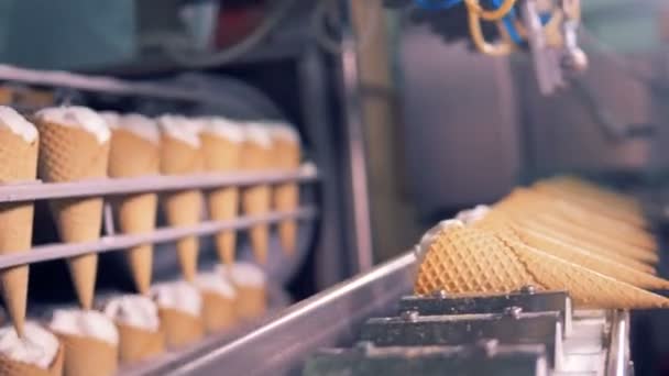 Заполненные вафельные конусы опускаются на конвейер — стоковое видео